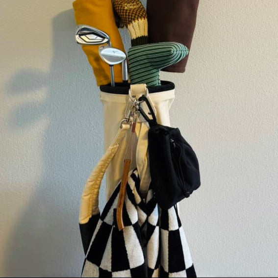 Golf clubs and bags hanging on a hook against a white wall